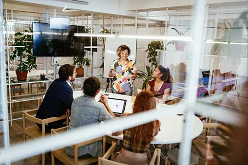 People sitting around a table in a glass walled meeting room.