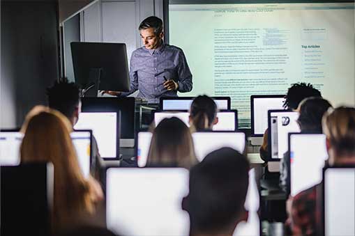 Instructor teaching a class with students sitting at computers.