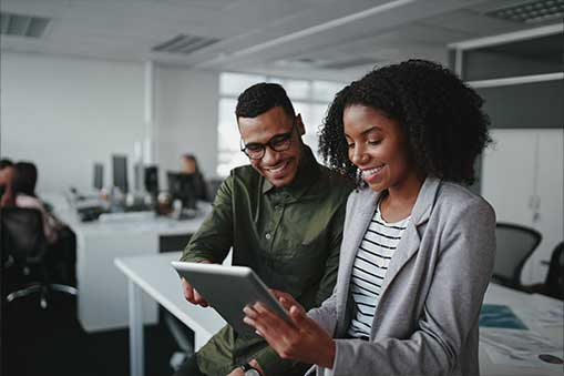 Two people in an office looking at a tablet